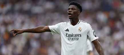 Manchester United nu renunță la visul Tchouaméni. Real Madrid are un acord verbal, dar transferul nu este exclus  Aurélien Tchouaméni continuă să fie unul dintre cele mai importante obiective ale lui Manchester United în această perioadă de mercato. Deși Real Madrid a ajuns la un acord verbal cu internaționalul francez pentru prelungirea contractului, oficializarea documentelor întârzie, iar pe Old Trafford încă există speranța că mutarea ar putea deveni posibilă.  Gruparea pregătită de Michael Carrick își propune să întărească serios compartimentul median înaintea noului sezon, în care va reveni în Liga Campionilor și speră să se implice în lupta pentru titlul din Premier League. După transferurile lui Youri Tielemans și Andrey Santos, conducerea clubului caută încă un mijlocaș cu profil defensiv, iar Tchouaméni rămâne numele aflat în fruntea listei.  Real Madrid nu a închis complet ușa  Potrivit informațiilor apărute în presa britanică, Real Madrid nu intenționează să renunțe la internaționalul francez. Graeme Bailey a relatat anterior că oficialii madrileni îl consideră un fotbalist important pentru viitorul echipei, chiar dacă în același timp analizează și posibilitatea transferului lui Rodri de la Manchester City.  În ultimele zile s-a scris că Tchouaméni și Real Madrid au ajuns la un acord verbal pentru un nou contract. Cum însă documentele nu au fost încă semnate și nici anunțate oficial, Manchester United continuă să urmărească atent evoluția situației.  Jurnalistul Ben Jacobs susține că înțelegerea există, însă până la oficializare orice scenariu rămâne deschis.  „Există un acord verbal. Dacă noul contract nu va fi finalizat, problema principală nu va fi salariul jucătorului, ci suma pe care o va cere Real Madrid.”  Potrivit acestuia, dificultatea nu ar fi negocierile cu fotbalistul, ci pretențiile financiare ale clubului spaniol.  „Ar fi posibil să se ajungă la un acord cu Tchouaméni, însă totul depinde de prețul solicitat de Real Madrid.”  Jacobs consideră că Manchester United ar reacționa imediat dacă situația s-ar schimba.  „Dacă s-ar deschide chiar și foarte puțin această posibilitate, iar suma ar fi una potrivită, Manchester United ar încerca transferul.”  În opinia jurnalistului, francezul rămâne obiectivul principal al clubului englez.  „Teoretic, Tchouaméni este principala țintă.”  Totuși, negocierile nu pot fi considerate active în acest moment.  „Practic însă nu putem spune că se lucrează la transfer, deoarece există deja un acord verbal pentru noul contract, iar în orice moment Real Madrid îl poate oficializa.”  Manchester United are pregătite și variante de rezervă  Conducerea de pe Old Trafford nu își construiește întreaga strategie în jurul unui singur nume și analizează mai multe opțiuni pentru postul de mijlocaș defensiv.  Pe lista de monitorizare se află Alex Scott și Tyler Adams, ambii legitimați la Bournemouth, dar și Manu Koné, fotbalistul celor de la AS Roma.  Ben Jacobs este convins că Manchester United va aduce încă un mijlocaș înainte de închiderea perioadei de transferuri, însă alegerea finală va depinde de evoluția negocierilor din următoarele săptămâni.  Alex Scott pare greu de transferat  În ceea ce îl privește pe Alex Scott, șansele unui transfer sunt reduse, deoarece Bournemouth nu pare dispusă să renunțe la unul dintre cei mai promițători jucători ai săi.  „Chelsea este în avantaj, pentru că a făcut deja o ofertă, iar Manchester United nu.”  Jacobs a infirmat și informațiile privind o eventuală clauză de aproximativ 60 de milioane de lire sterline.  „Informațiile potrivit cărora Scott ar putea pleca pentru 60 de milioane de lire sterline au fost exagerate.”  Mai mult, mesajele venite din interiorul clubului sunt clare.  „Sursele din Bournemouth spun că se așteaptă ca Scott să rămână la club și în acest sezon.”  Tyler Adams costă mai mult decât se credea  O altă variantă urmărită este Tyler Adams. În cazul internaționalului american, suma vehiculată în spațiul public nu ar reflecta realitatea.  „S-a vorbit despre un preț de 35 de milioane de lire sterline, dar suma cerută este considerabil mai mare.”  Acest lucru face ca o eventuală mutare să fie mult mai complicată decât părea inițial.  Manu Koné, cea mai accesibilă opțiune  Dintre toate variantele analizate, Manu Koné pare în prezent cea mai ușor de transferat.  AS Roma este dispusă să ia în calcul ofertele primite, însă numai în schimbul unei sume importante.  „Prețul lui Koné este undeva între 45 și 50 de milioane de euro.”  Jacobs susține că formația italiană nu se află într-o situație care să o oblige să accepte un transfer sub valoarea dorită.  „Roma are nevoie să încaseze bani din transferuri, dar a fost activă pe piață și nu este într-o situație disperată, astfel că nu va accepta o ofertă sub valoarea dorită.”  Tchouaméni rămâne marele vis al lui United  În paralel, alte informații apărute în presa internațională susțin că Aurélien Tchouaméni nu ar respinge o mutare pe Old Trafford, dacă vor fi rezolvate cele două obstacole considerate decisive pentru realizarea transferului.  Și Fabrizio Romano a confirmat în mai multe rânduri că interesul lui Manchester United este autentic. În același timp, jurnalistul italian a explicat că Real Madrid ar putea avea nevoie de o vânzare importantă pentru a obține fondurile necesare unei eventuale ofensive pentru Rodri, mijlocaș evaluat la aproximativ 60 de milioane de euro.